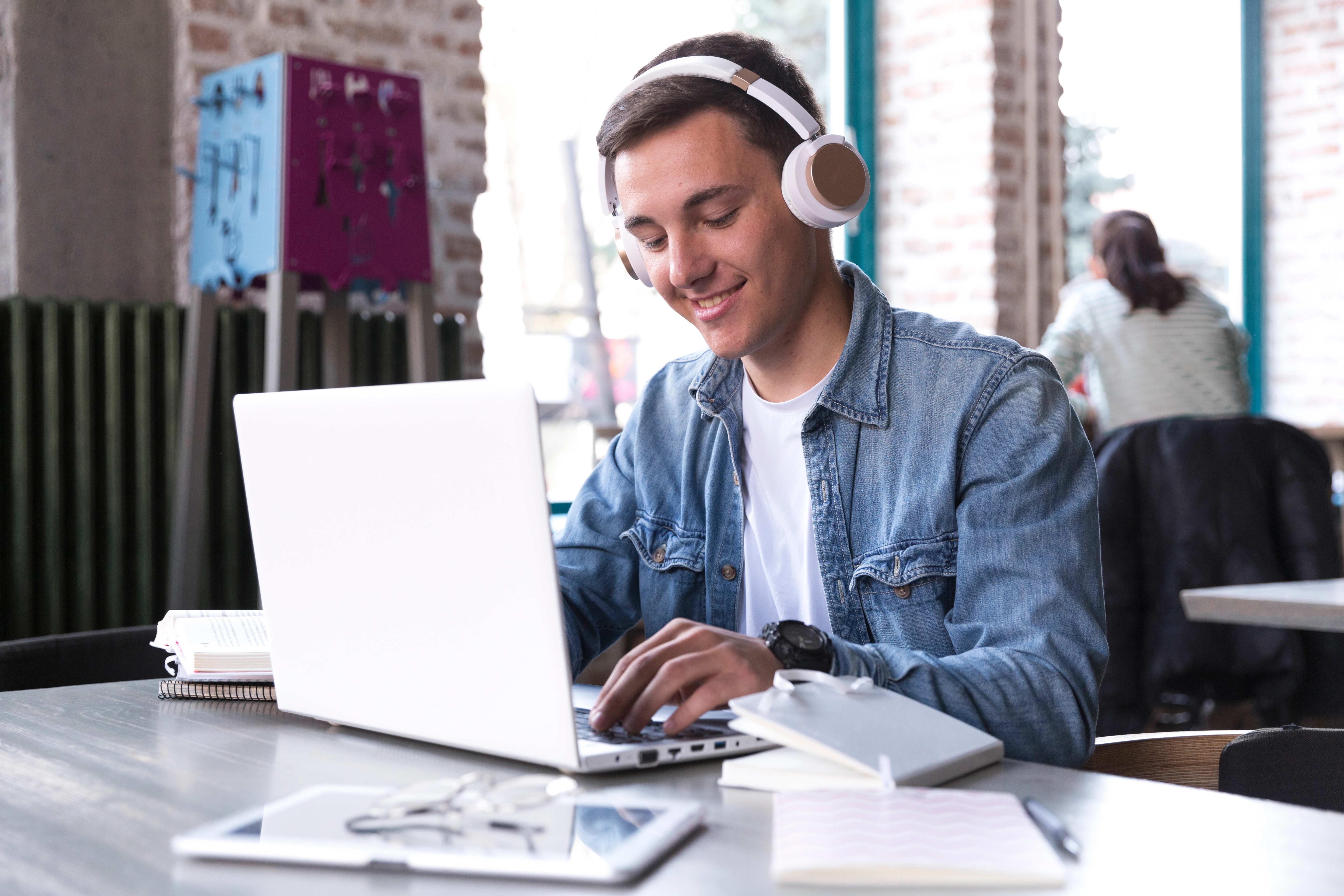 teenage-student-headphones-sitting-table-typing-notebook.webp