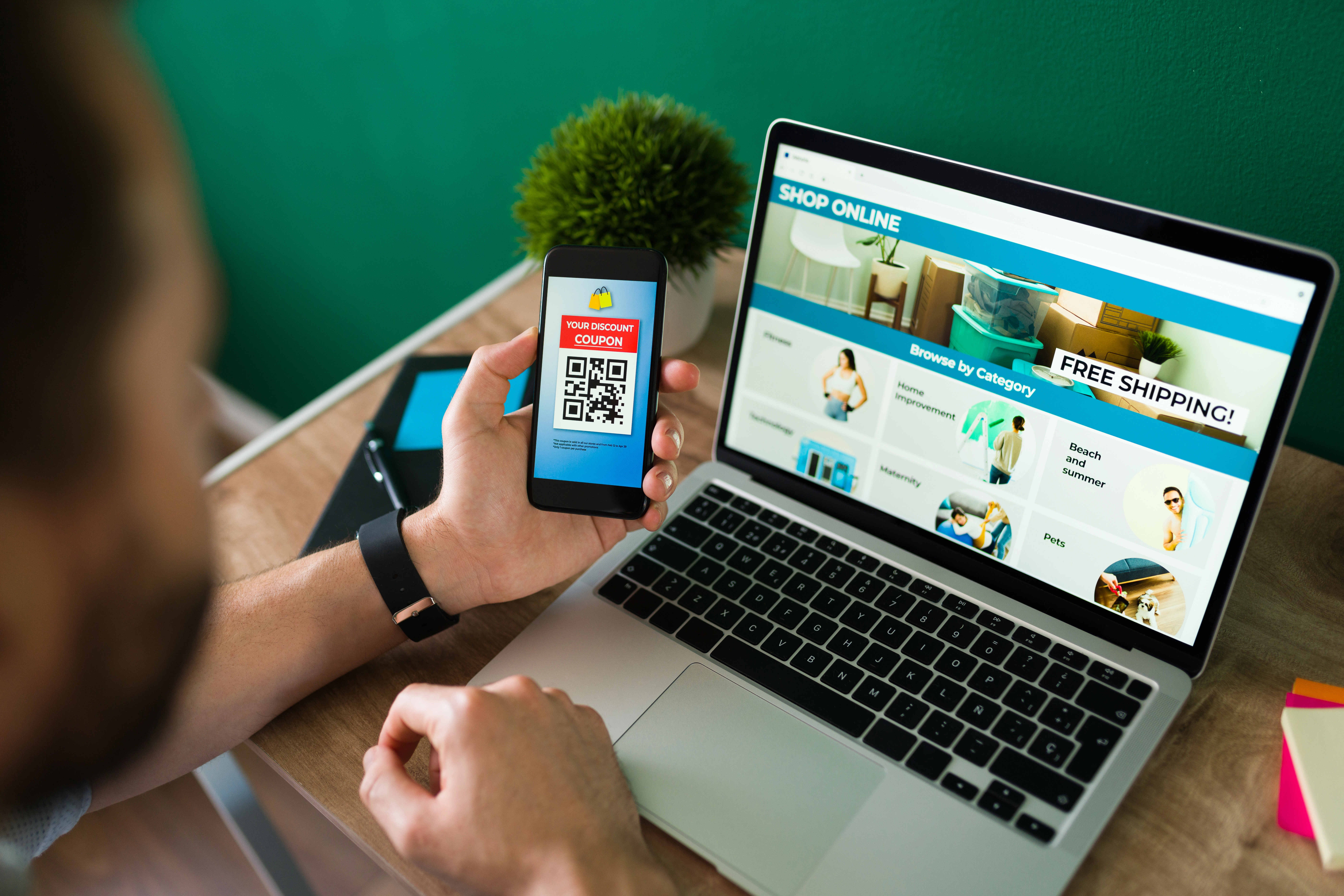 young-man-using-discount-coupon-his-smartphone-some-online-shopping-laptop.webp